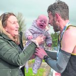 Omagh Harriers runner Colly Harkin gets passed his 4 month old daughter Hailey by his mum Bernie after crossing the finish line at the Omagh Half Marathon. JasMc56
